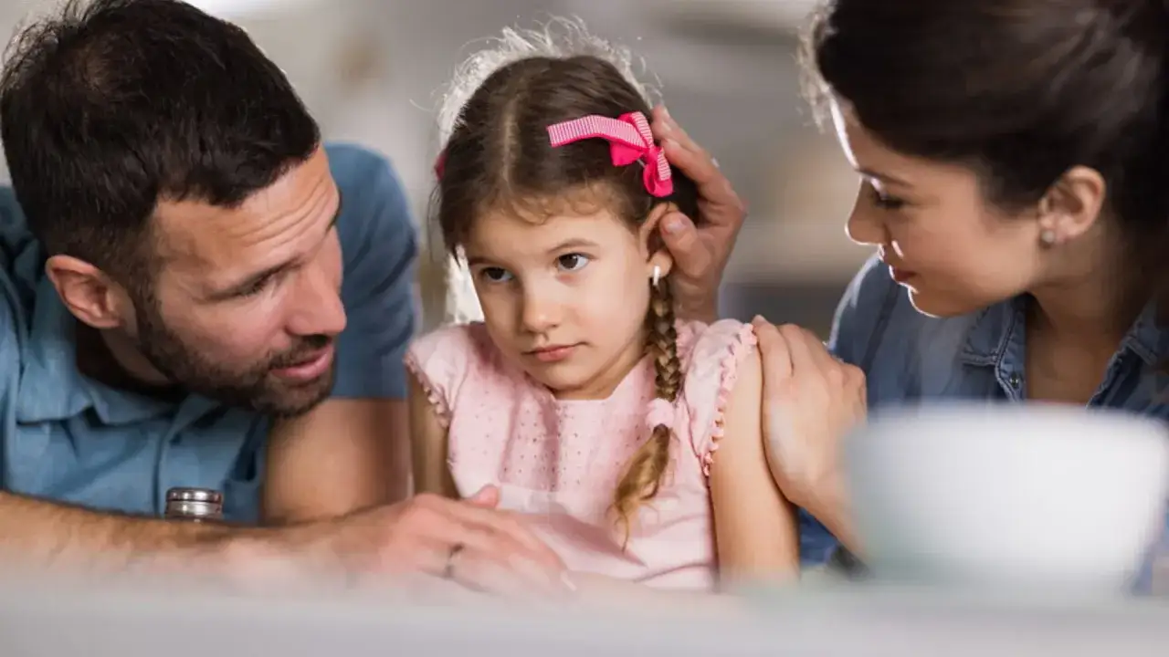 Genitori parlano con la figlia, spiegando come dire ai figli che i genitori si separano. La bambina appare pensierosa.