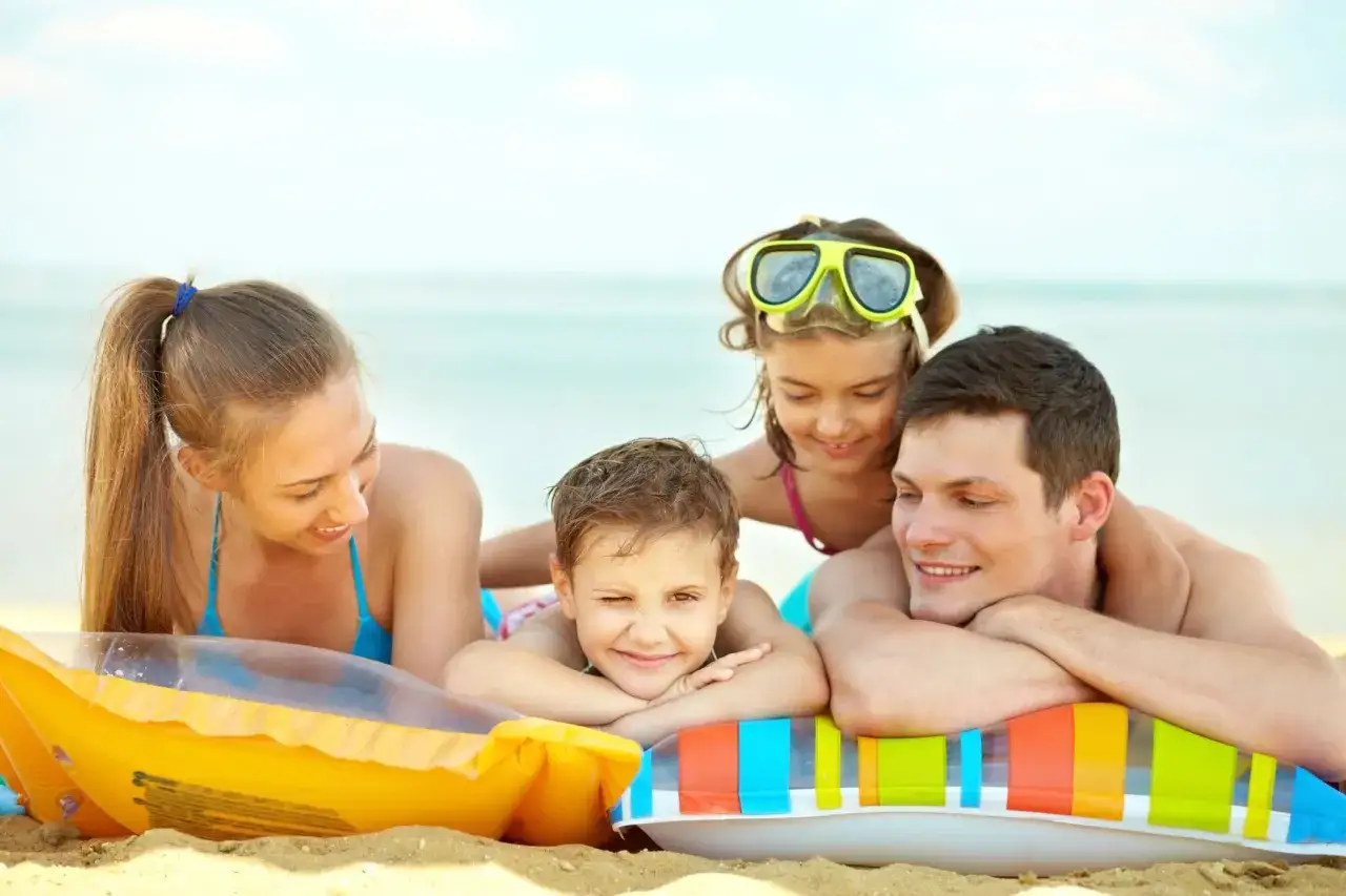 Famiglia felice in spiaggia, un'idea su cosa fare a Ferragosto con i bambini: relax e divertimento al mare.