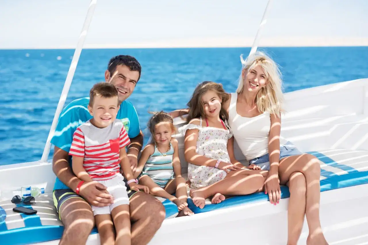 Famiglia felice in barca, un'idea perfetta su cosa fare a Ferragosto con i bambini per godersi il mare e il sole.