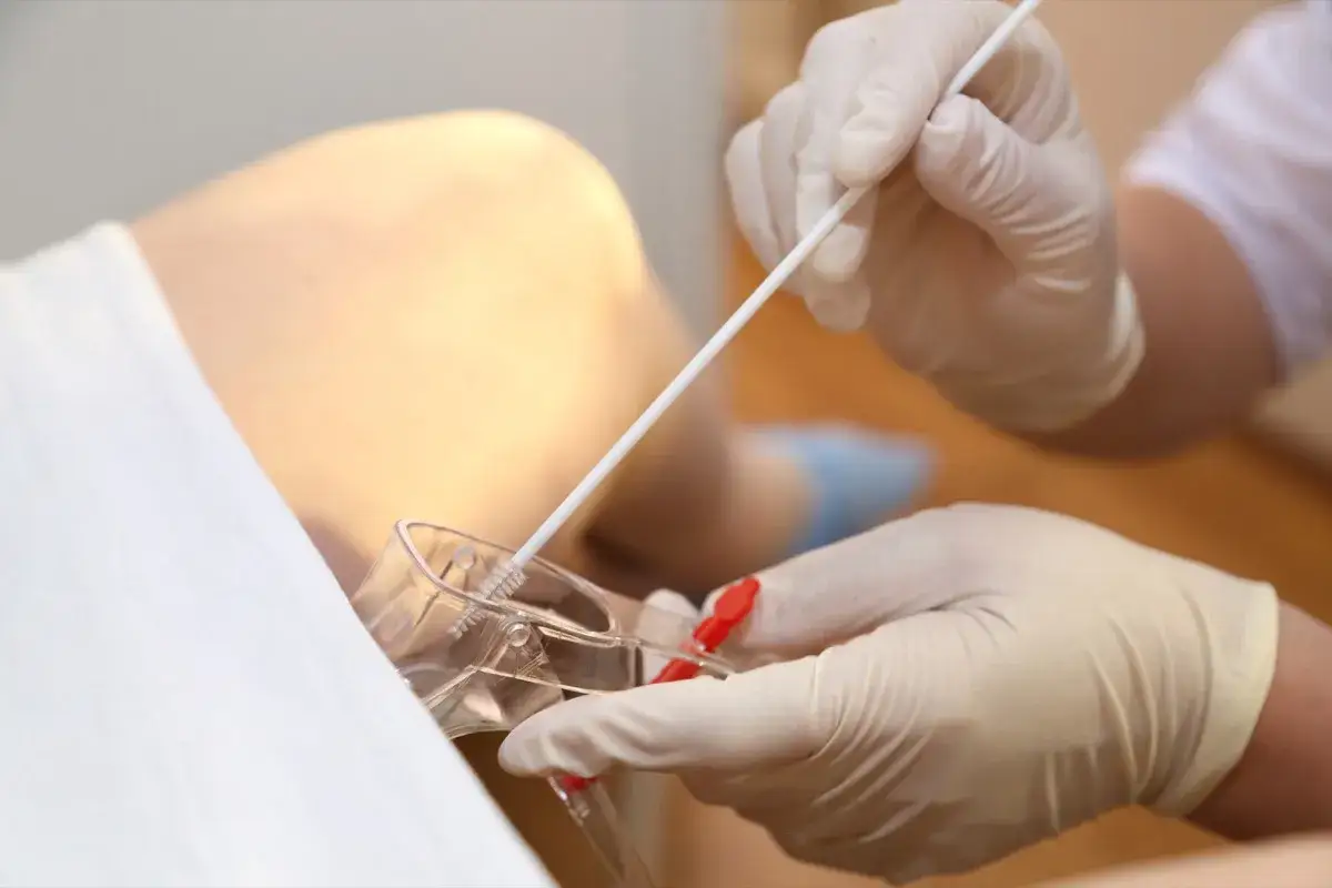 Mani guantate preparano un tampone vaginale per un esame, forse per una gravidanza.