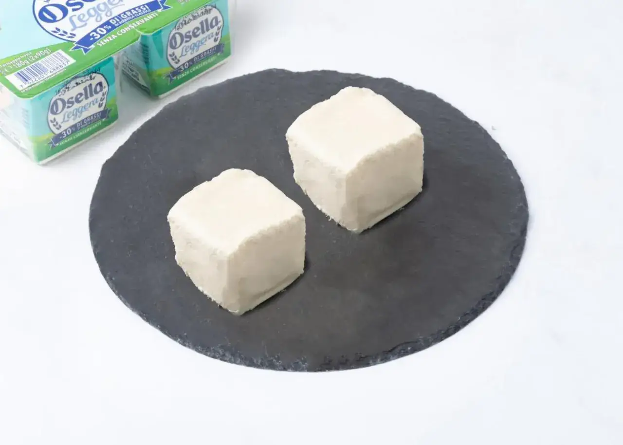 Due cubetti di robiola Osella Leggera su una pietra scura, ideali per chi cerca un'opzione leggera in gravidanza.