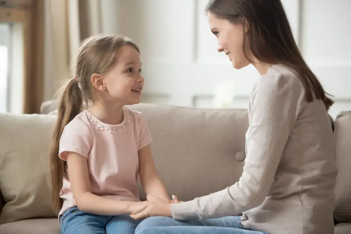 Bambina sorride alla madre, tenendole le mani. Chissà se un giorno mi chiamerà mamma.