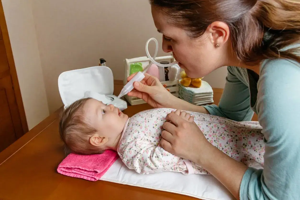 Mamma usa aspiratore nasale per liberare il neonato dal muco, evitando il soffocamento.