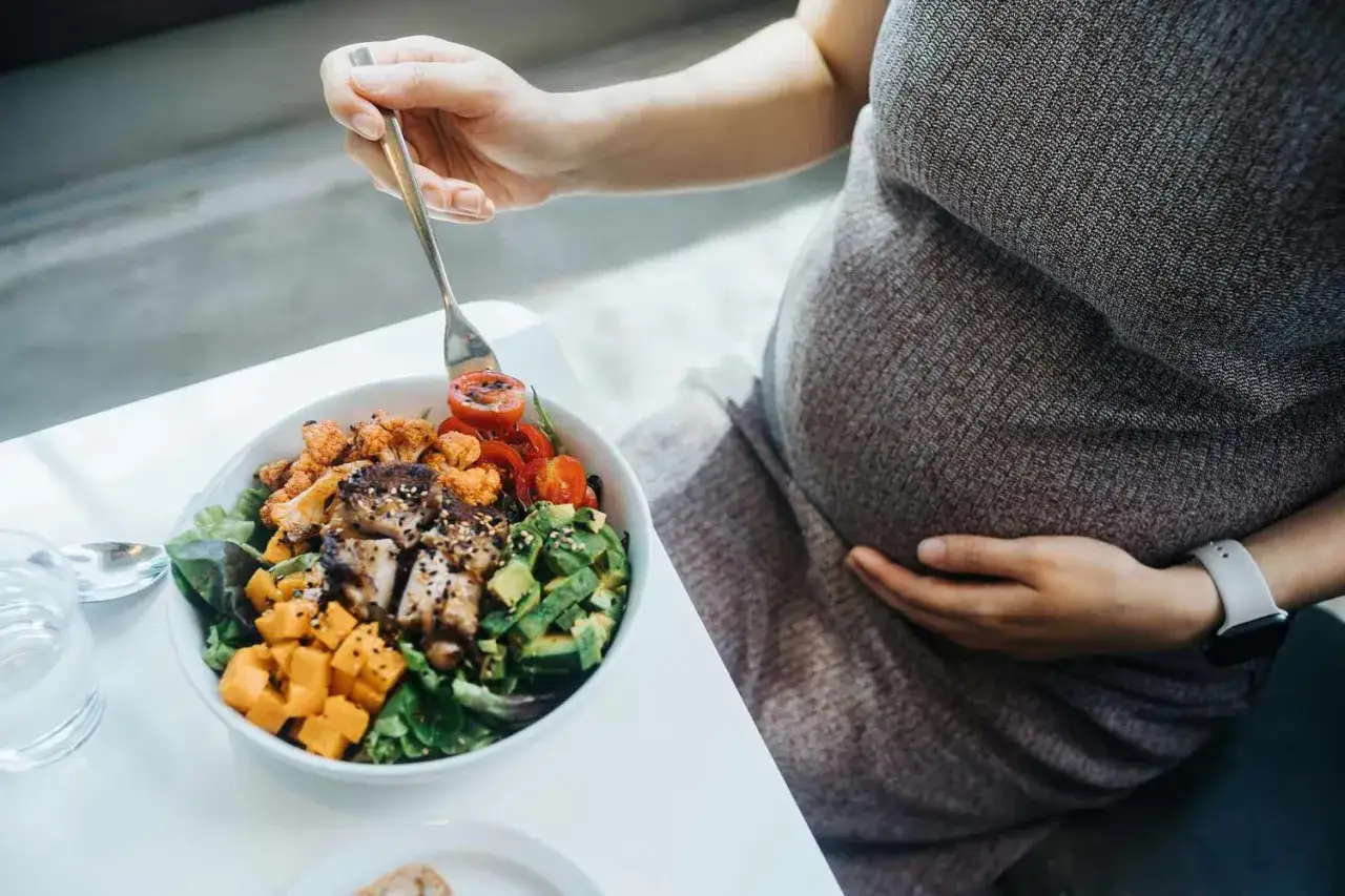 Donna incinta mangia un'insalata nutriente. L'acido folico prima o dopo i pasti è importante per la salute.