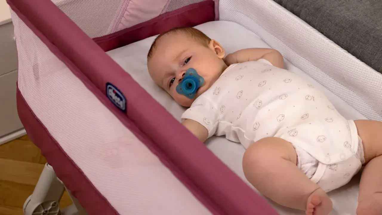 Un neonato con ciuccio blu giace nel lettino. Forse i neonati sognano incubi, ma questo sembra tranquillo.