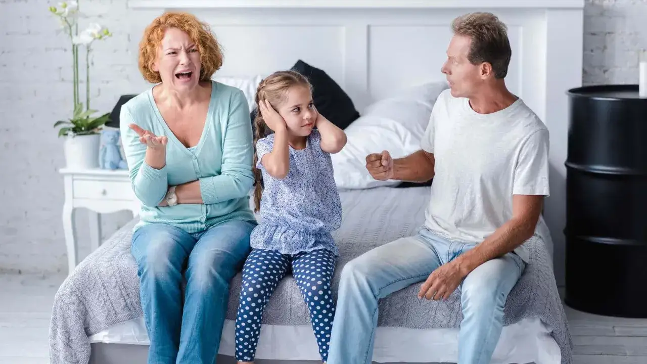 Coppia litiga davanti alla figlia che si tappa le orecchie. La bambina soffre nel vedere i genitori litigare davanti a lei.