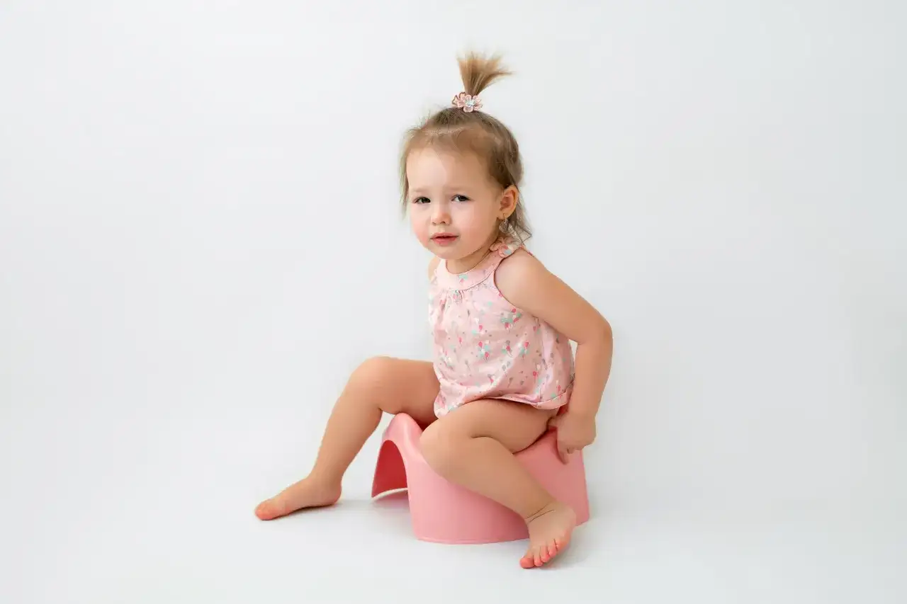 Bambina seduta sul vasino rosa, in un momento di intimità, mentre impara a fare la cacca.