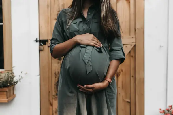 Donna incinta con mani sul pancione, in attesa di un bambino. Un momento di gioia che spesso include l'analisi sangue gravidanza.